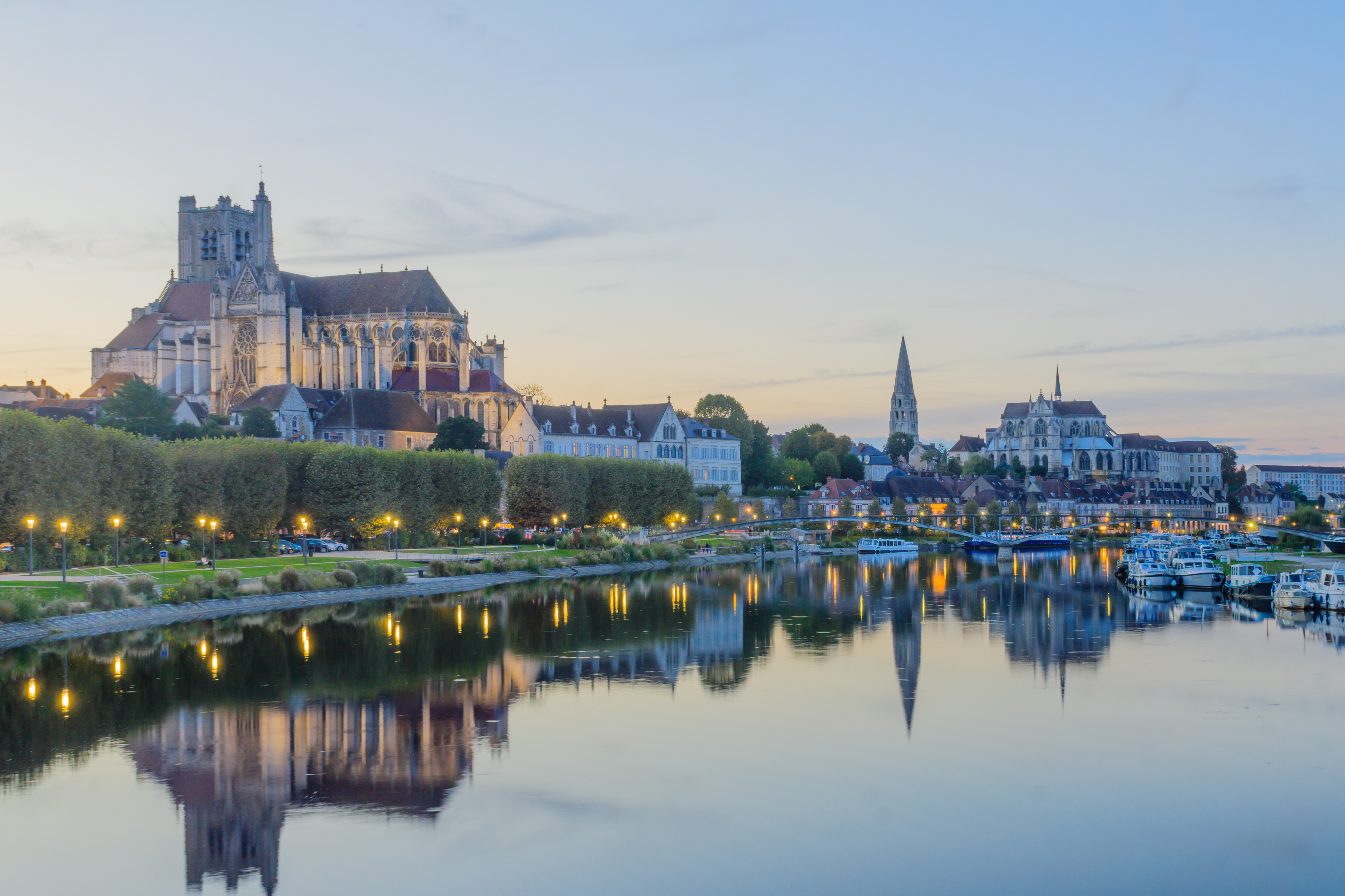 Sunset view of the Yonne River, with boats, the cathedral (Cathedrale Saint-Etienne), the Abbey of Saint-Germain, locals and visitors, in Auxerre, Burgundy, France